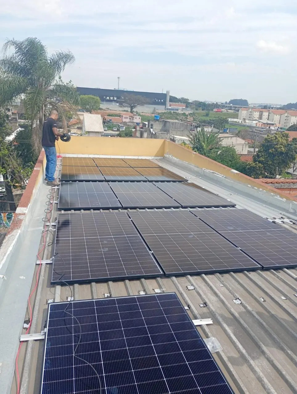 Telhado com módulos de energia solar instalados e a cidade ao fundo